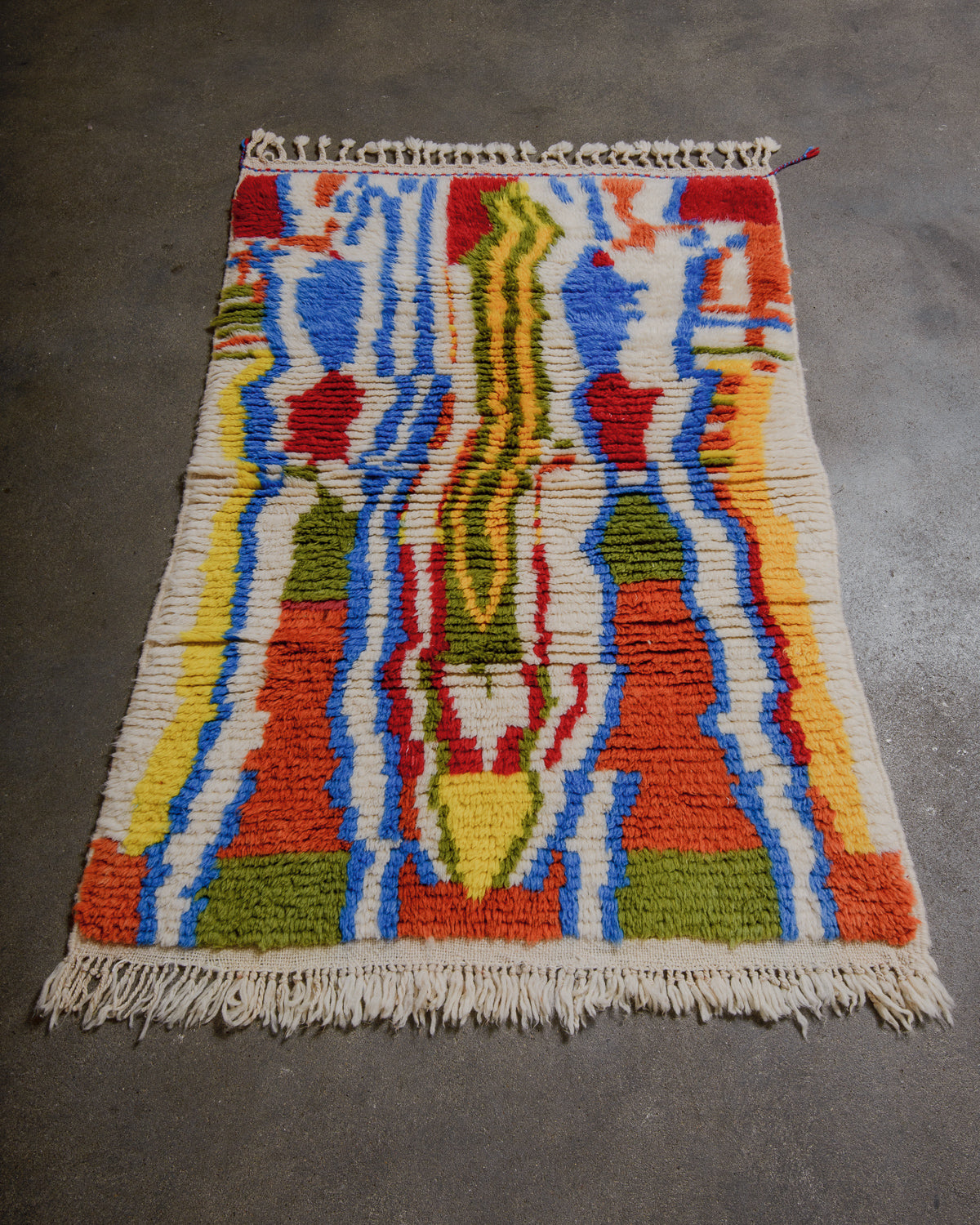 Colorful woven wool rug with abstract pattern on a gray floor